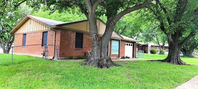 view of home's exterior with a yard, board and batten siding, brick siding, fence, and an attached garage