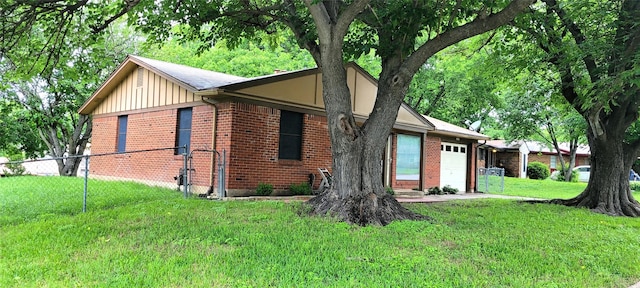 view of side of home with a yard, fence, a garage, and brick siding