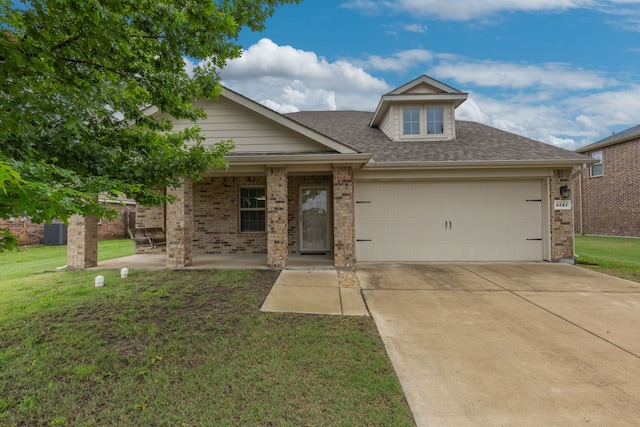 view of front of home featuring a front yard, brick siding, an attached garage, and driveway