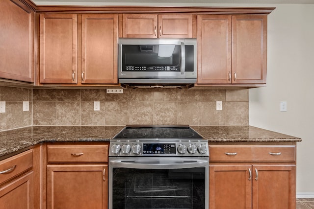 kitchen featuring brown cabinets, dark stone counters, and appliances with stainless steel finishes