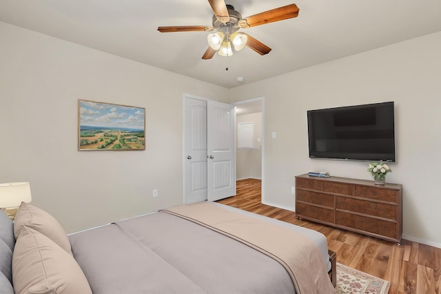 bedroom with a ceiling fan, wood finished floors, and baseboards