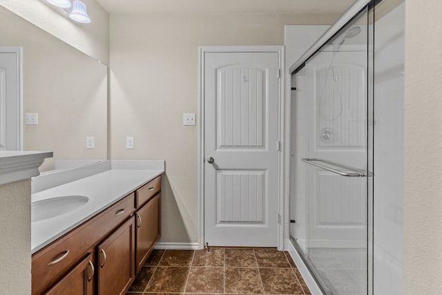 bathroom featuring a stall shower, vanity, and baseboards