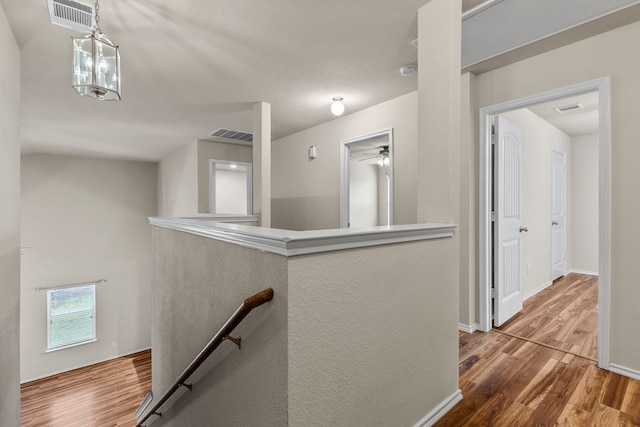 hall with wood finished floors, an upstairs landing, and visible vents