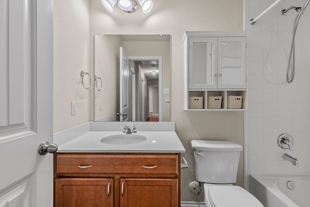 full bath featuring toilet, vanity, shower / washtub combination, and a textured wall
