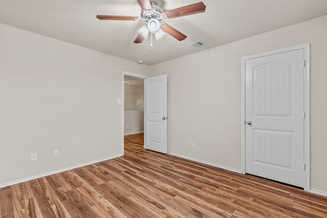 unfurnished bedroom with visible vents, wood finished floors, and baseboards