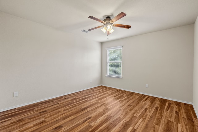 unfurnished room with a ceiling fan, baseboards, visible vents, and wood finished floors