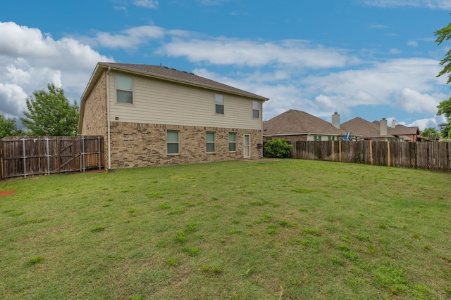 rear view of property featuring a fenced backyard, brick siding, and a lawn