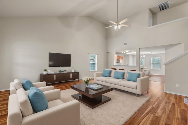 living room with baseboards, ceiling fan, visible vents, high vaulted ceiling, and light wood-type flooring