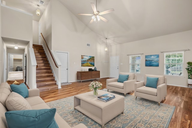 living room featuring stairs, wood finished floors, high vaulted ceiling, visible vents, and a ceiling fan