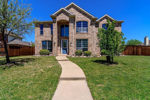 traditional-style home featuring a front yard, brick siding, and fence