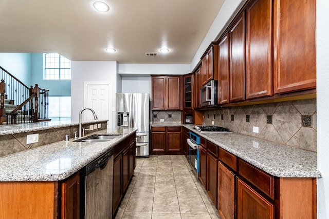 kitchen with light stone counters, visible vents, a sink, stainless steel appliances, and tasteful backsplash