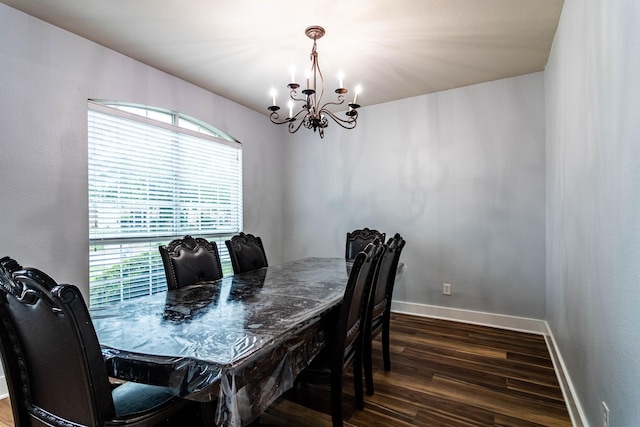 dining area featuring a chandelier, dark wood finished floors, and baseboards