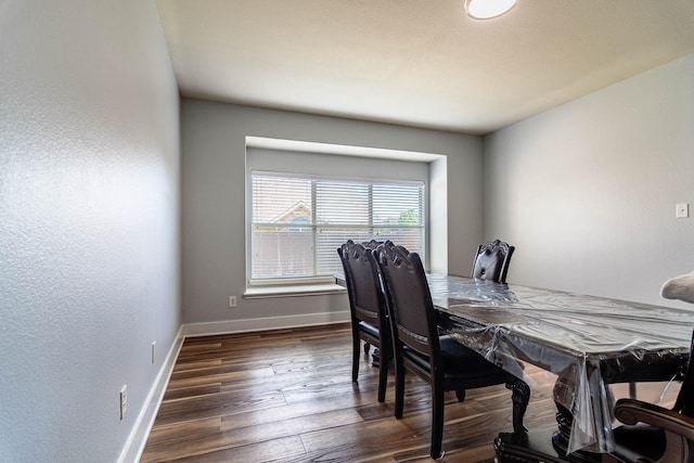 dining space with baseboards and dark wood-type flooring