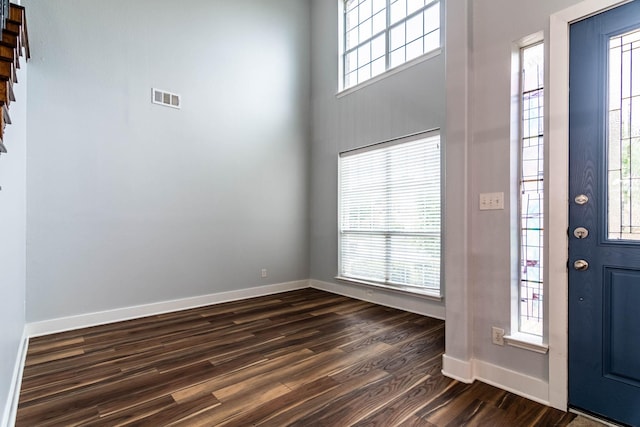 foyer entrance with a high ceiling, baseboards, visible vents, and dark wood finished floors