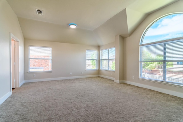 unfurnished room featuring carpet flooring, vaulted ceiling, and visible vents
