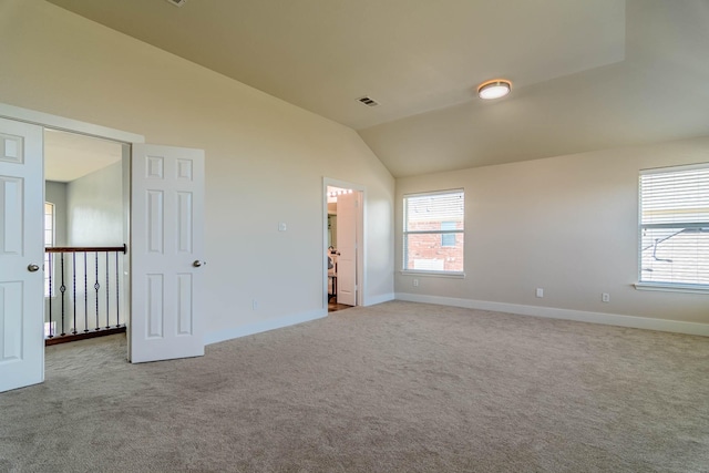 carpeted spare room featuring vaulted ceiling, plenty of natural light, and baseboards