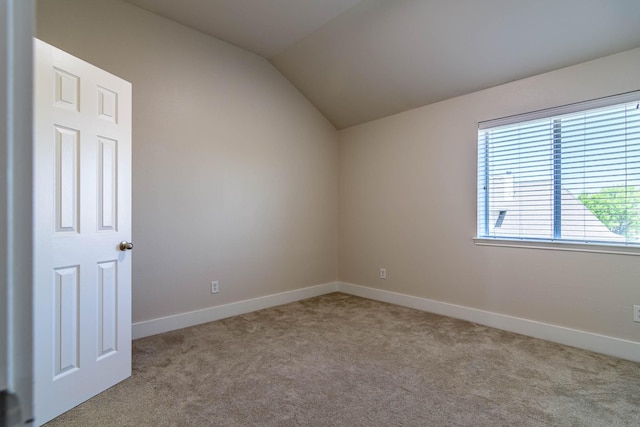 empty room with vaulted ceiling, carpet, and baseboards