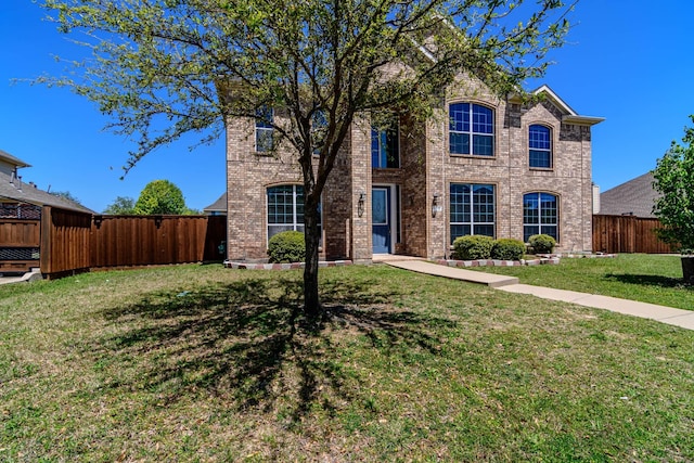 view of front of property featuring a front lawn, brick siding, and fence