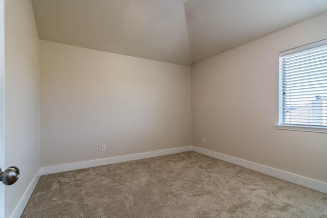 spare room featuring vaulted ceiling, baseboards, and carpet floors
