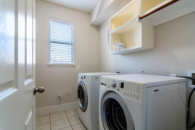 washroom with washer and clothes dryer, light tile patterned flooring, and baseboards
