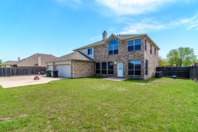 back of house featuring a chimney, a lawn, an attached garage, central AC unit, and a fenced backyard