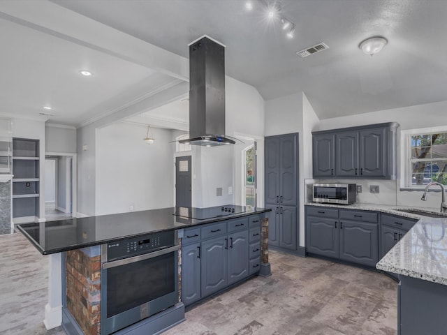 kitchen with stainless steel appliances, a sink, island range hood, a kitchen island, and light stone counters