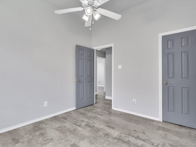 unfurnished bedroom featuring baseboards, a high ceiling, and ceiling fan
