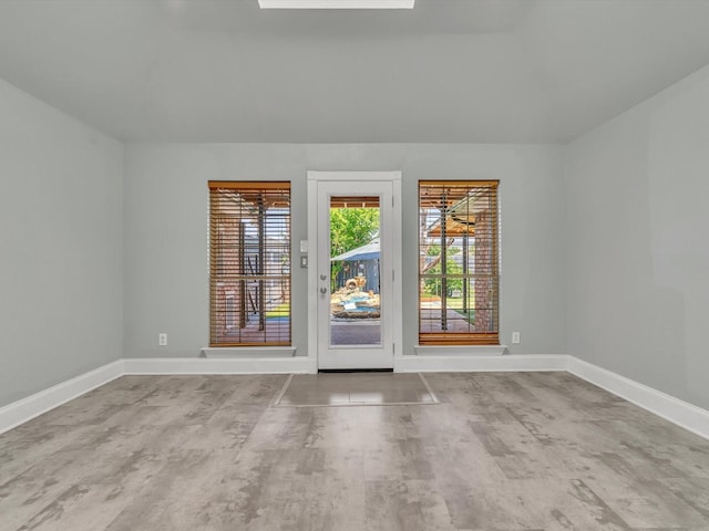 unfurnished room with baseboards and vaulted ceiling