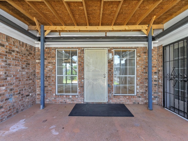 doorway to property featuring brick siding and a patio area