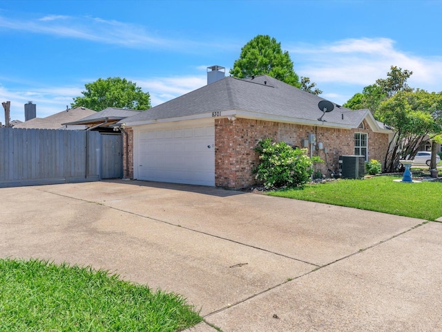 view of side of property with an attached garage, brick siding, concrete driveway, cooling unit, and a chimney