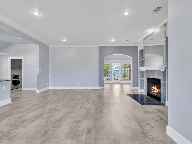 unfurnished living room with washer / clothes dryer, recessed lighting, a fireplace, crown molding, and built in features