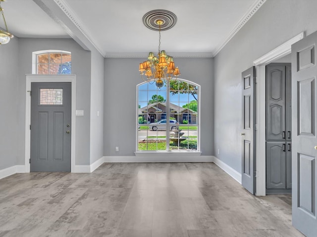 entrance foyer with a chandelier, ornamental molding, and baseboards