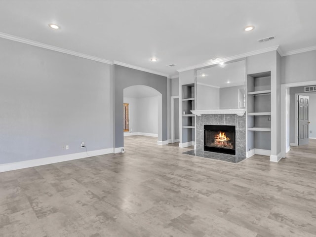 unfurnished living room with arched walkways, crown molding, baseboards, built in features, and a fireplace