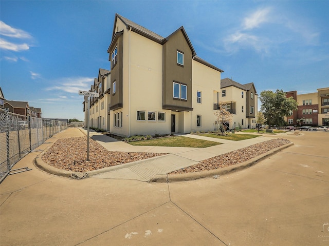 exterior space with stucco siding, fence, and a residential view