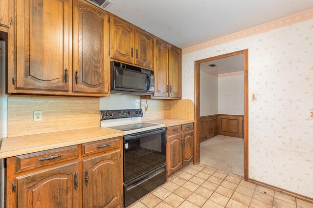 107 Russell Dr, Highland Village, TX 75077 - kitchen with electric range, black microwave, wallpapered walls, light countertops, and a wainscoted wall