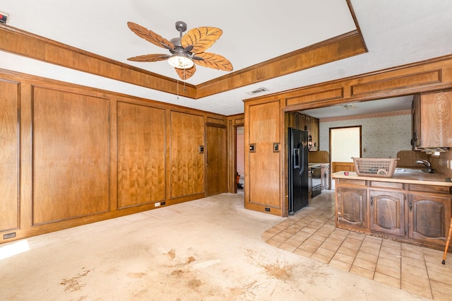 107 Russell Dr, Highland Village, TX 75077 - kitchen with black fridge, a ceiling fan, a raised ceiling, brown cabinetry, and light countertops