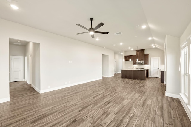 unfurnished living room featuring a ceiling fan, wood finished floors, recessed lighting, baseboards, and vaulted ceiling