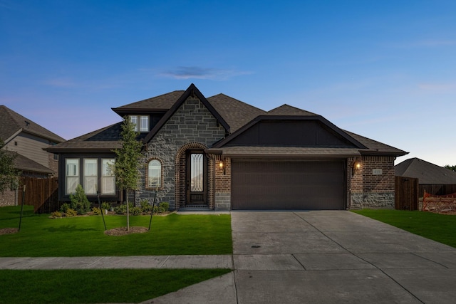 french country home featuring stone siding, a garage, driveway, and brick siding