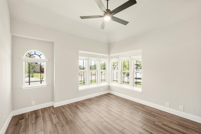 spare room featuring wood finished floors, a ceiling fan, and baseboards