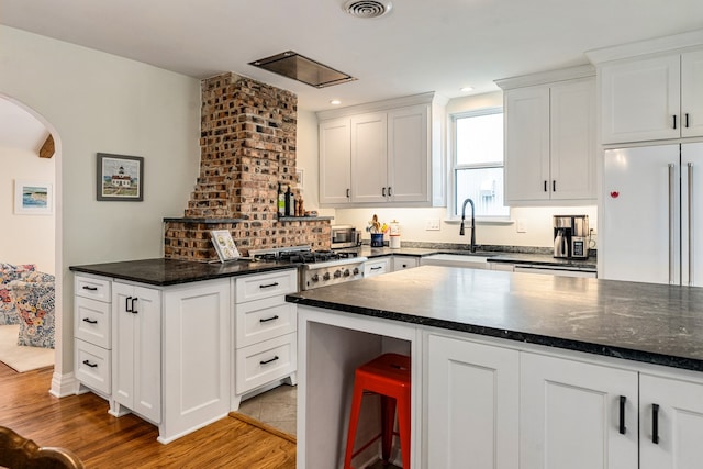 5107 Milam St, Dallas, TX 75206 - kitchen with a sink, white cabinets, light wood-type flooring, arched walkways, and stainless steel gas stovetop
