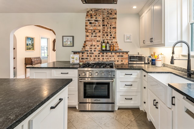 5107 Milam St, Dallas, TX 75206 - kitchen with recessed lighting, stainless steel stove, a sink, arched walkways, and white cabinets
