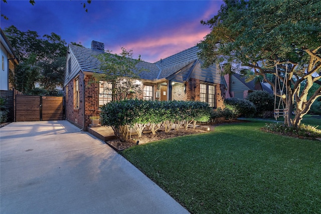 5107 Milam St, Dallas, TX 75206 - view of front facade with brick siding, driveway, a chimney, and a lawn