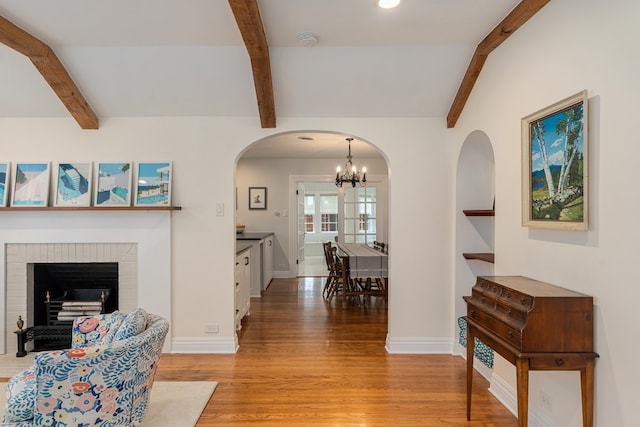 5107 Milam St, Dallas, TX 75206 - living room with beam ceiling, an inviting chandelier, arched walkways, baseboards, and light wood-style floors