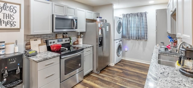1773 Westview Dr, Abilene, TX 79603 - kitchen featuring stainless steel appliances, estacked washer and dryer, dark wood-style floors, decorative backsplash, and light stone countertops