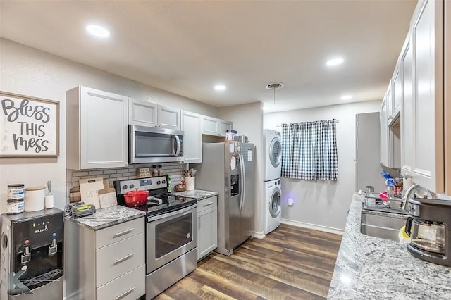 1773 Westview Dr, Abilene, TX 79603 - kitchen featuring appliances with stainless steel finishes, stacked washer / dryer, a sink, dark wood finished floors, and tasteful backsplash