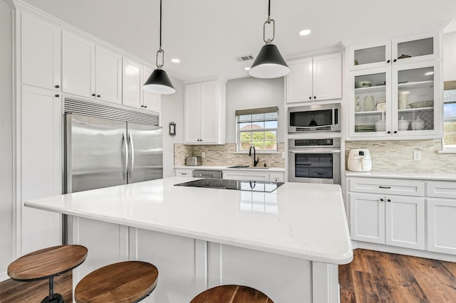 kitchen with a sink, stainless steel appliances, white cabinets, visible vents, and tasteful backsplash