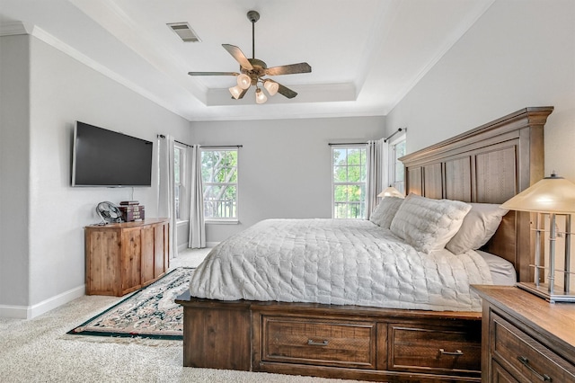 bedroom featuring light colored carpet, ornamental molding, visible vents, a tray ceiling, and baseboards