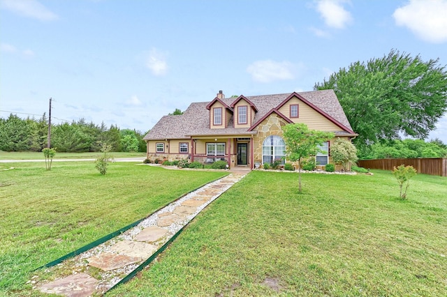 view of front facade featuring stone siding, fence, a chimney, and a front yard