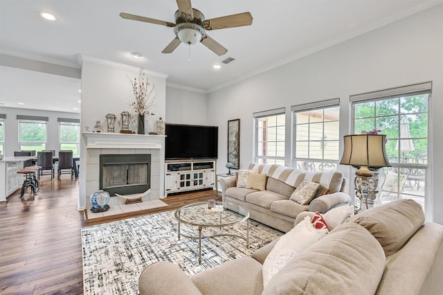 living area featuring wood finished floors, visible vents, ceiling fan, ornamental molding, and recessed lighting