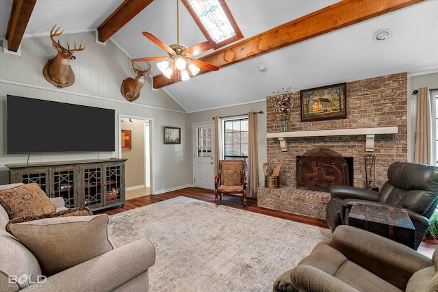 living area with lofted ceiling with beams, wood finished floors, a fireplace, ceiling fan, and baseboards